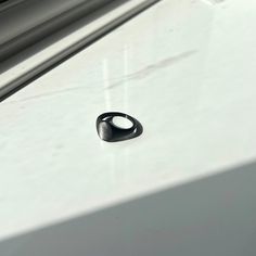 a black ring sitting on top of a white surface next to a window sill