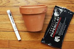 a pen, plant and chocolate bar sitting on a wooden floor next to a packet of candy