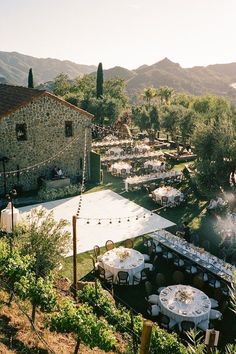 an outdoor venue with tables and chairs set up in the middle of it, surrounded by greenery