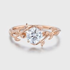 a rose gold ring with a white diamond in the center and leaves on each band