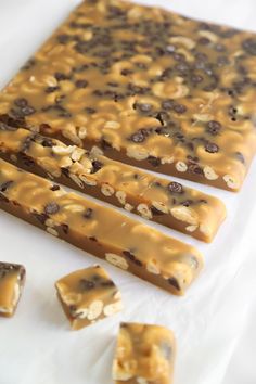 three pieces of chocolate and peanut butter granola bar on a white surface with five bars cut into squares