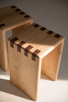 two wooden stools sitting next to each other on a white surface with brown stripes