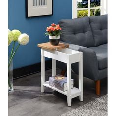 a living room with blue walls and a gray couch next to a table with flowers on it