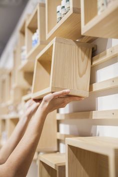 a person holding a wooden object in front of shelving unit with shelves on both sides