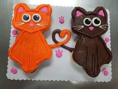 there are two decorated cookies with cats on the top one is orange and the other is brown