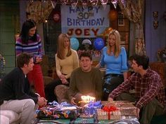 the cast of friends gathered around a birthday cake