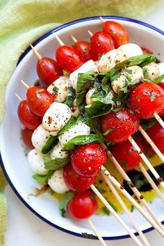 a white plate topped with tomatoes and mozzarella skewers