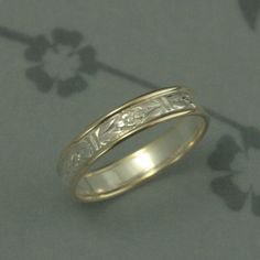 a gold wedding ring with an engraved design on the inside and outside, sitting on a gray surface