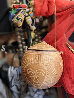 a wooden ball hanging from a string in front of a red netted cloth and other items