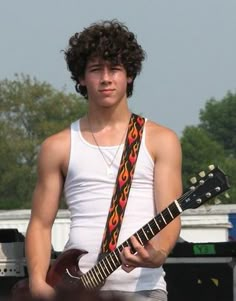 a young man is playing an electric guitar at a music festival in front of the stage