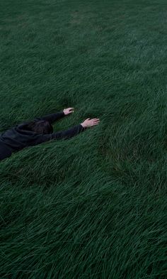 a person laying in the grass with their arms out