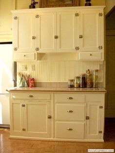 a kitchen with white cabinets and wooden floors