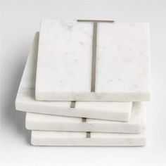 four white marble coasters stacked on top of each other with a metal cross in the middle