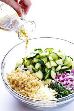 someone is pouring dressing into a bowl filled with chopped cucumbers and other vegetables