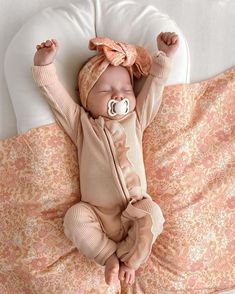 a baby laying on top of a bed with a pacifier in it's mouth