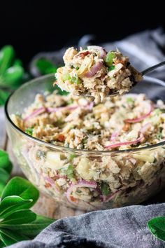 a person spooning food out of a glass bowl with green leaves around it on a table