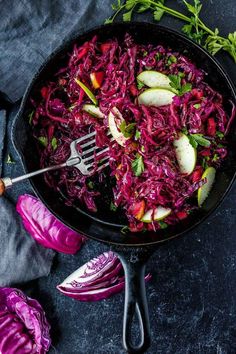 a skillet filled with red cabbage and apples