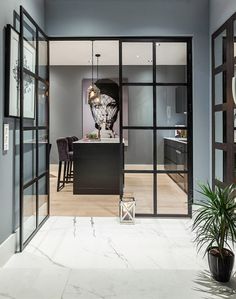 an open kitchen and dining area with glass doors leading to the living room, which is decorated in black and white