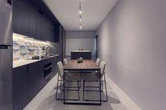 a kitchen with a table and chairs next to a refrigerator in the middle of it