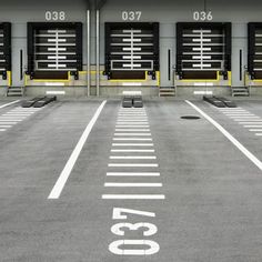 an empty parking lot with rows of doors and numbers painted on the ground in front of them