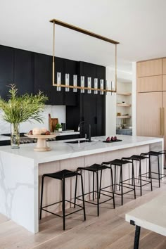 a kitchen with black cabinets, white countertops and bar stools next to an island