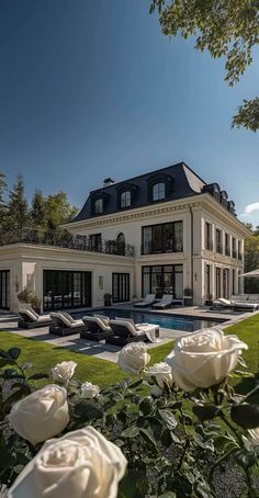 a large white house sitting on top of a lush green field next to a swimming pool