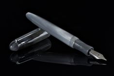 two fountain pens sitting next to each other on a black surface