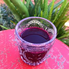 a glass filled with liquid sitting on top of a red table