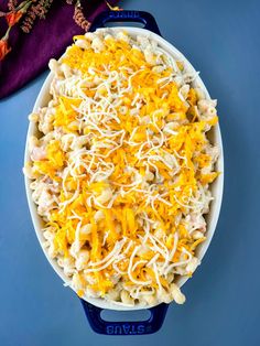 a casserole dish filled with macaroni and cheese on a blue surface