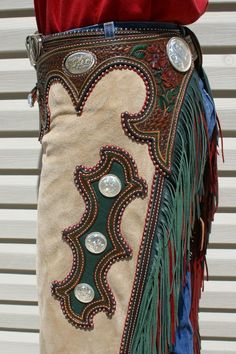 a woman wearing a skirt with fringes and buttons on it's side, standing in front of a building