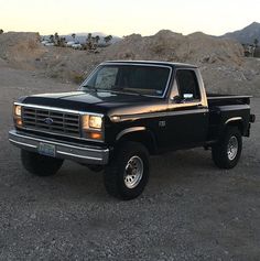 a black pickup truck parked on top of a dirt field