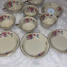 a bunch of dishes that are sitting on a white tablecloth with some pink and blue flowers