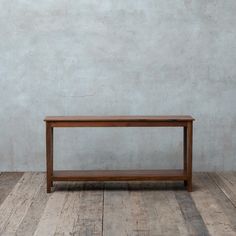 a wooden table sitting on top of a hard wood floor next to a white wall