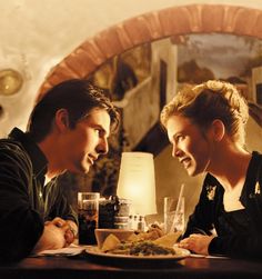 two people sitting at a table with food in front of them