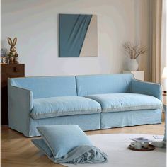 a blue couch sitting on top of a hard wood floor next to a white rug