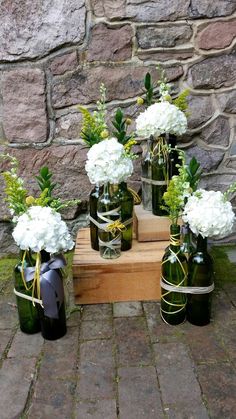 there are several vases with flowers in them on the ground next to a brick wall