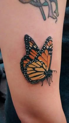 an orange and black butterfly tattoo on the arm