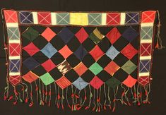 a black cloth with multicolored squares and tassels hanging from it's sides