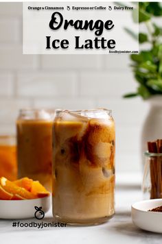 an orange iced latte in a glass with cinnamon sticks next to it on a counter