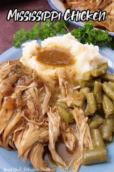 a blue plate topped with mashed potatoes and green beans covered in gravy