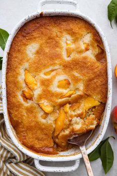 a casserole dish filled with peach cobbler and topped with fresh peaches