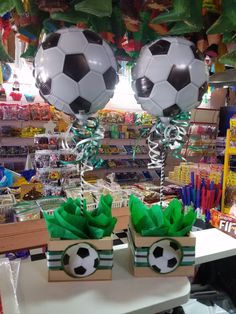 two boxes with soccer balls in them sitting on a table next to balloons and streamers