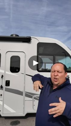 a man standing in front of an rv pointing to the side with his hand out