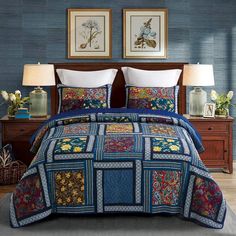 a bed with blue and red bedspread, two lamps and pictures on the wall