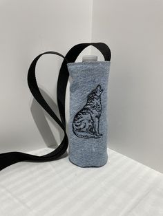 a bottle bag with a cat on it sitting on top of a white table next to a black strap