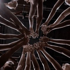 a group of people holding their hands together in a circle with the light shining on them