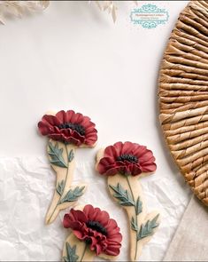 three cookies decorated with red flowers and leaves