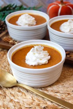 three bowls of pumpkin soup with whipped cream