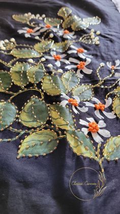 an embroidered table cloth with flowers and leaves on it