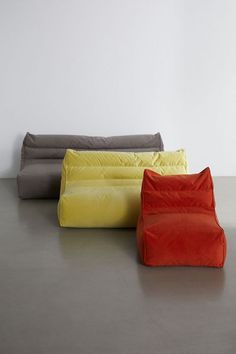 three different colored bean bags sitting next to each other on the floor in front of a white wall